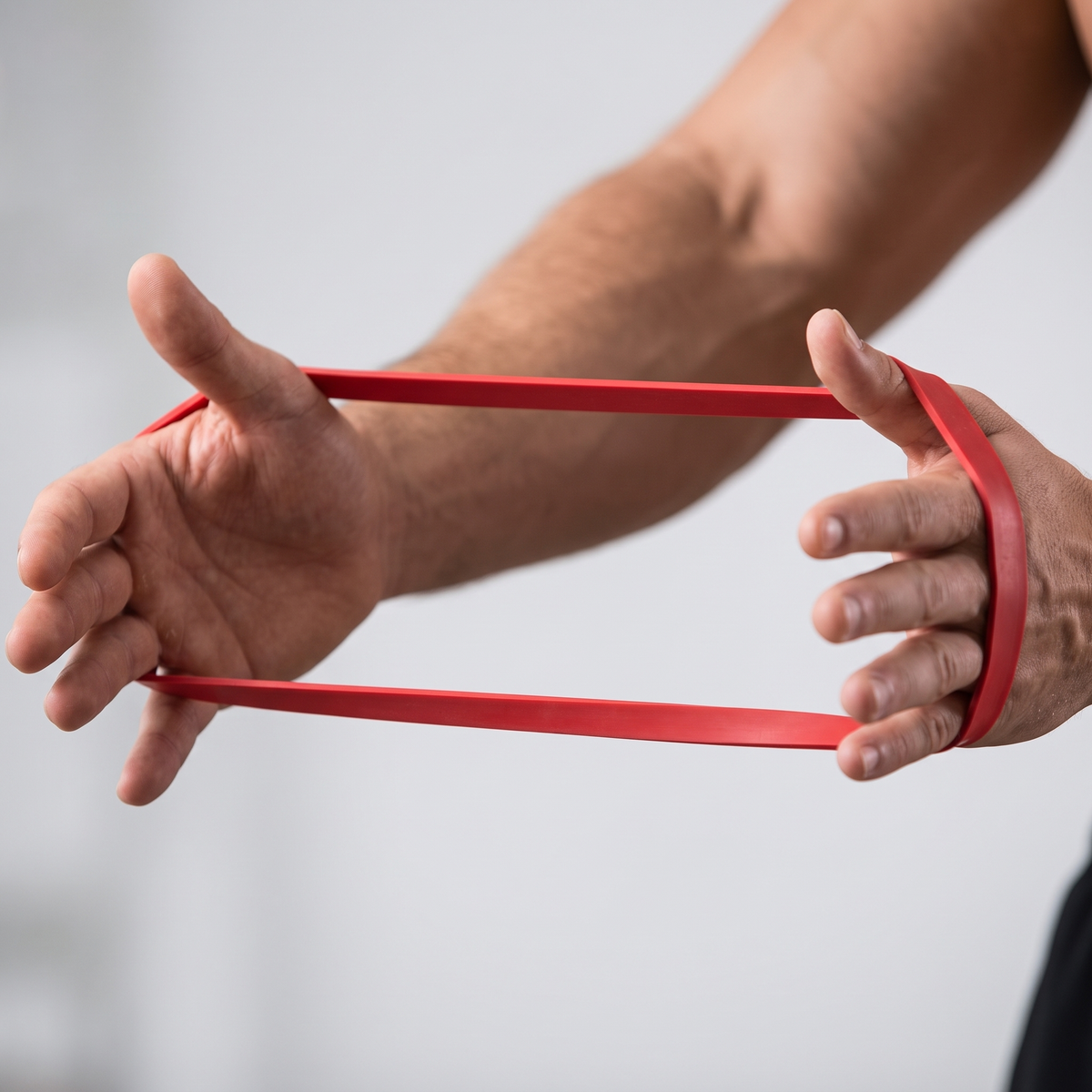 Gros plan sur la bande de résistance rouge en latex naturel tendue entre les mains
