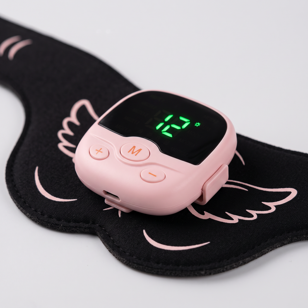 Boîtier de commande de la ceinture EMS fessiers clipsé sur le pad : écran LED, touche M et touches + et −