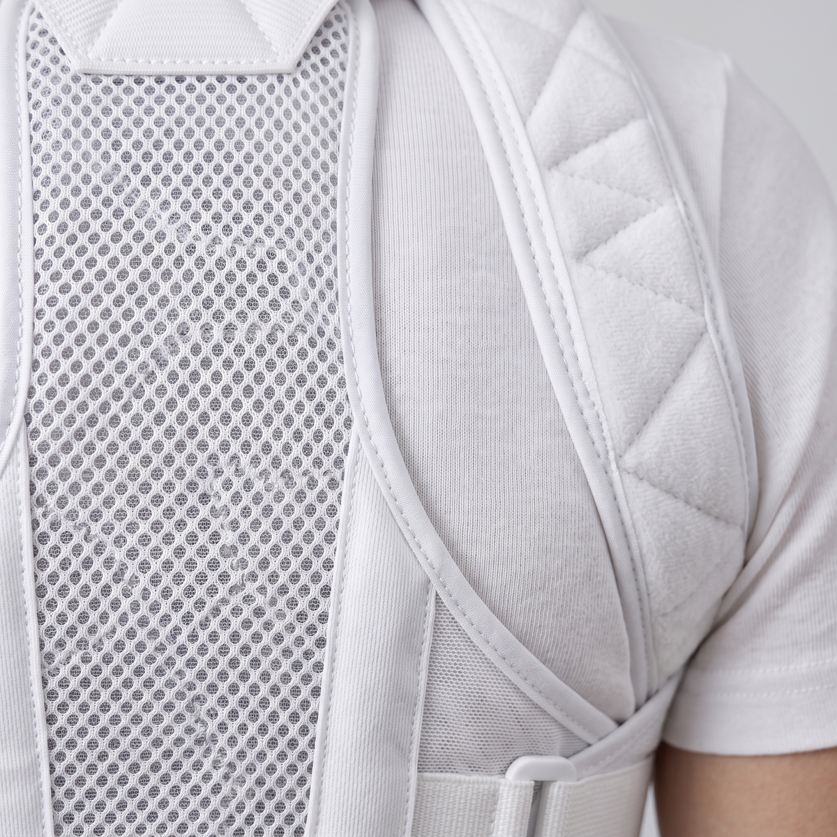 Détail du panneau dorsal en maille nid d'abeille respirante et de la bretelle rembourrée du correcteur de posture blanc