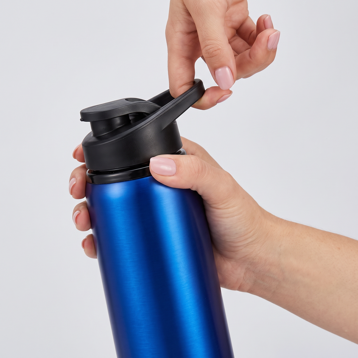 Gourde inox 700 ml tenue en main, doigt passé dans l'anse de transport