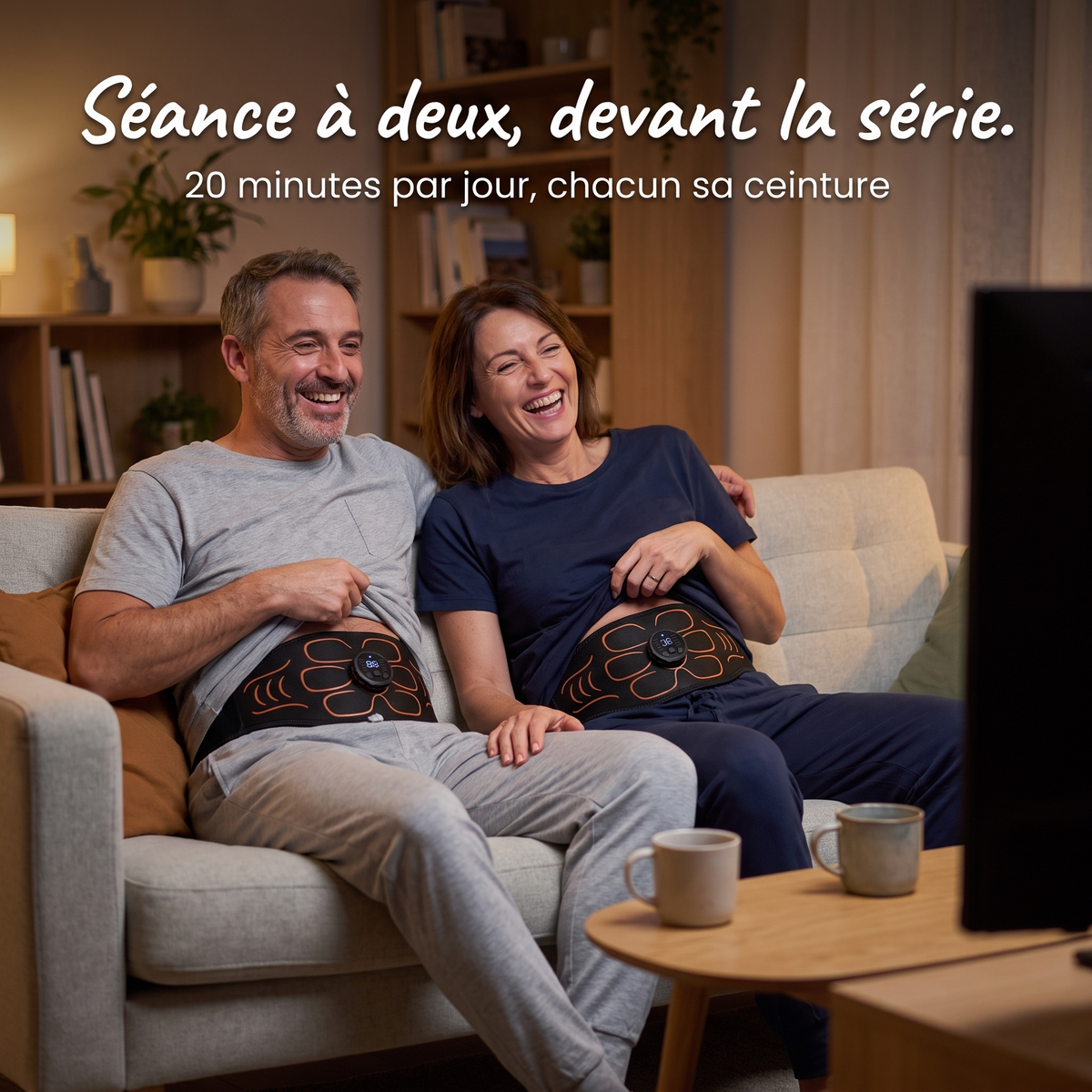 Couple sur le canapé portant chacun sa ceinture abdominale EMS devant une série, 20 minutes par jour