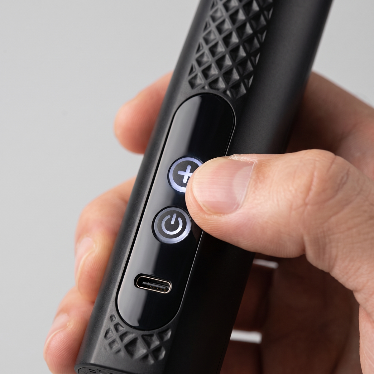 Détail des deux boutons de commande et du port USB-C du pistolet de massage