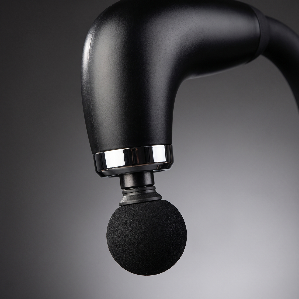 Gros plan sur la tête boule et la bague chromée du pistolet de massage